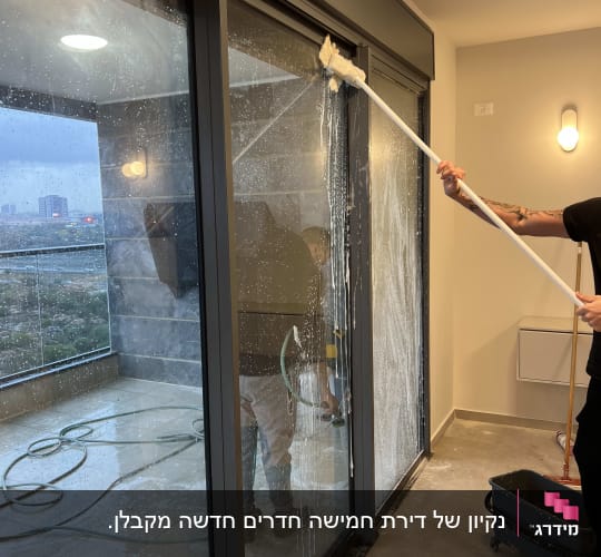 ניקוי חלונות עם מגב וסבון על מרפסת